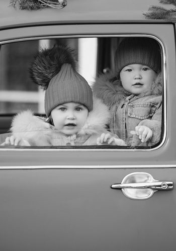 two-cute-little-kids-winter-clothes-peeking-out-window-bright-red-car